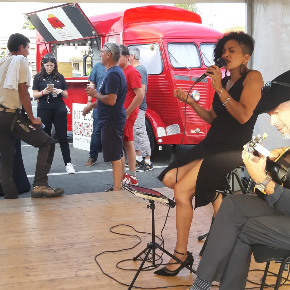 Performance musicale près d'un food truck Chanteuse et musicien devant un food truck rouge